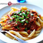 A plate of protein pasta topped with lean beef and tomato basil sauce, garnished with chopped herbs